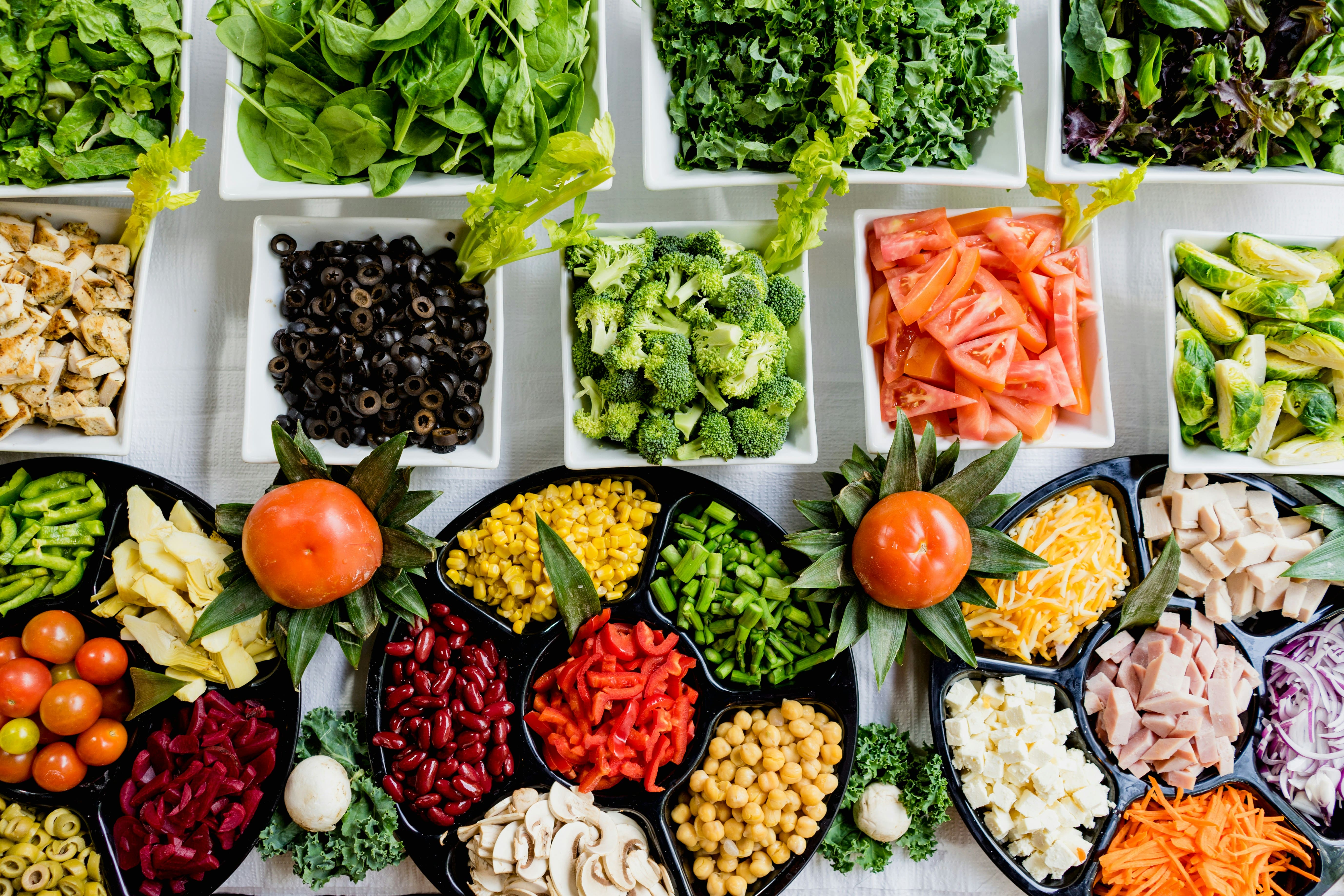 Top-down view of a colorful salad bar with fresh vegetables, greens, and proteins for meal planning